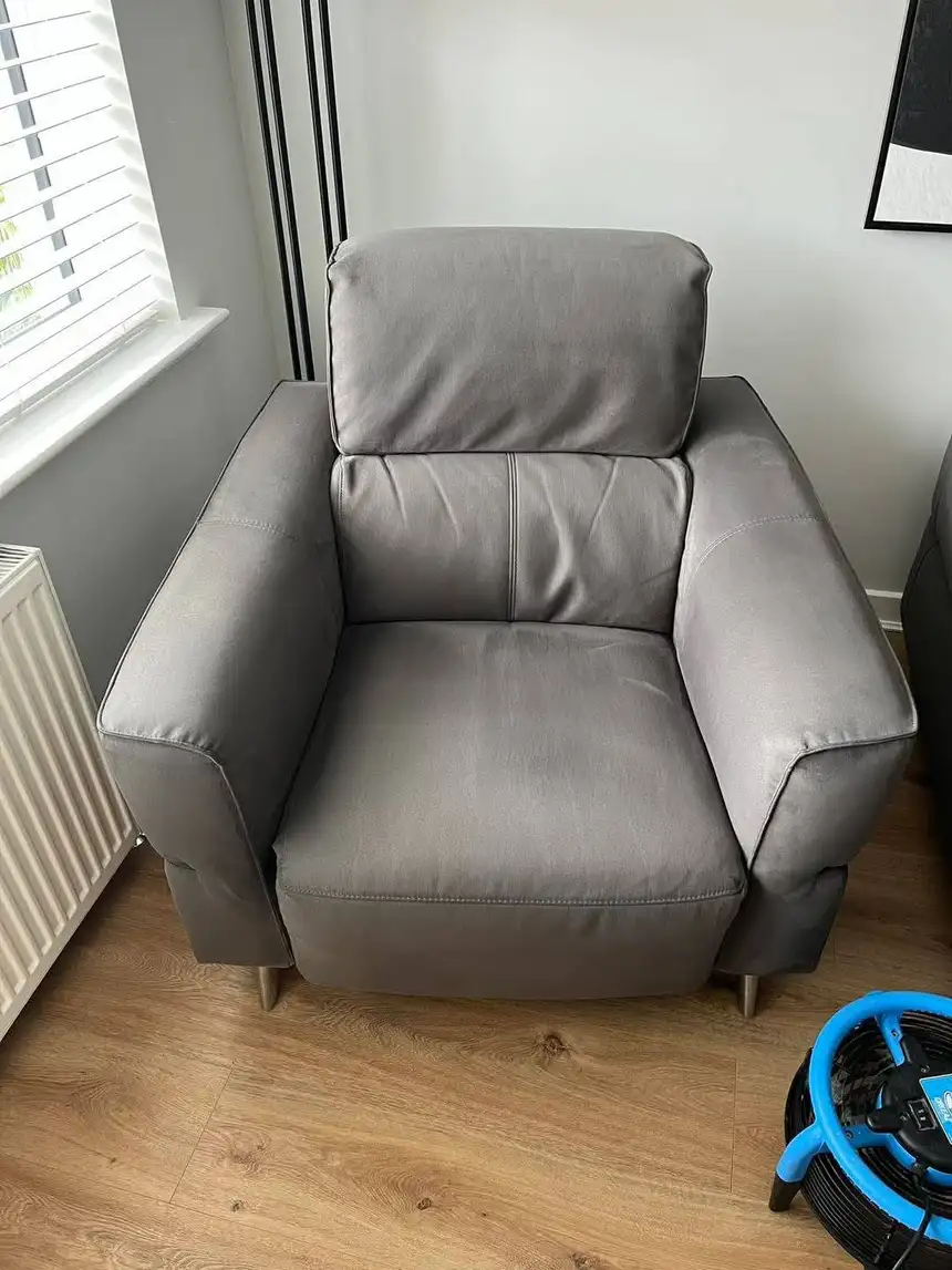 Grey fabric armchair cleaned to an even tone with a blue drying fan beside it