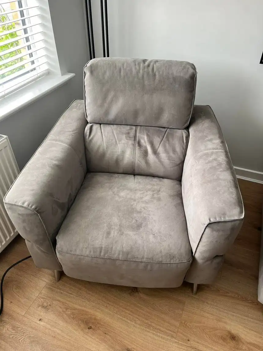 Grey fabric armchair with mottled watermark patches and soiling on seat and arms