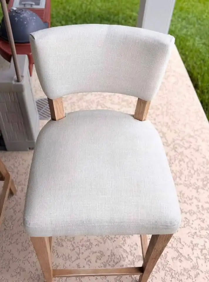 Cream linen bar stool on a patio with even off-white upholstery after cleaning