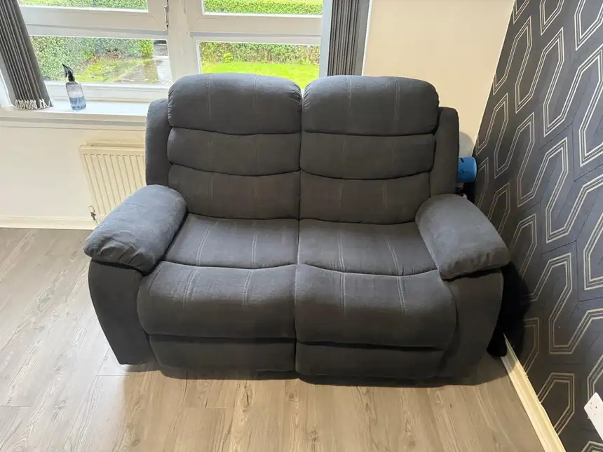 Grey fabric two-seater recliner sofa with dulled, darkened cushions before cleaning