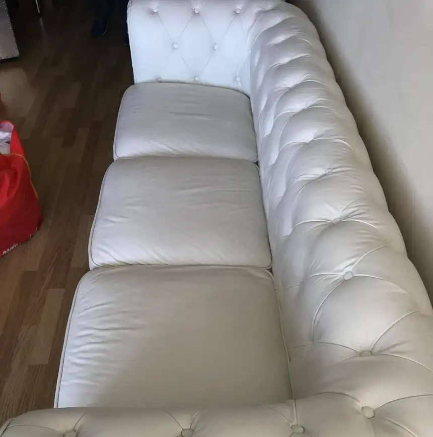 White leather chesterfield sofa with uniformly bright white cushions after cleaning